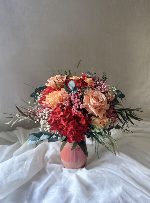 Bouquet de fleurs éternelles Siena avec des teintes corail, pêche, rouge, blanc et rose, dans un style bohème chic.